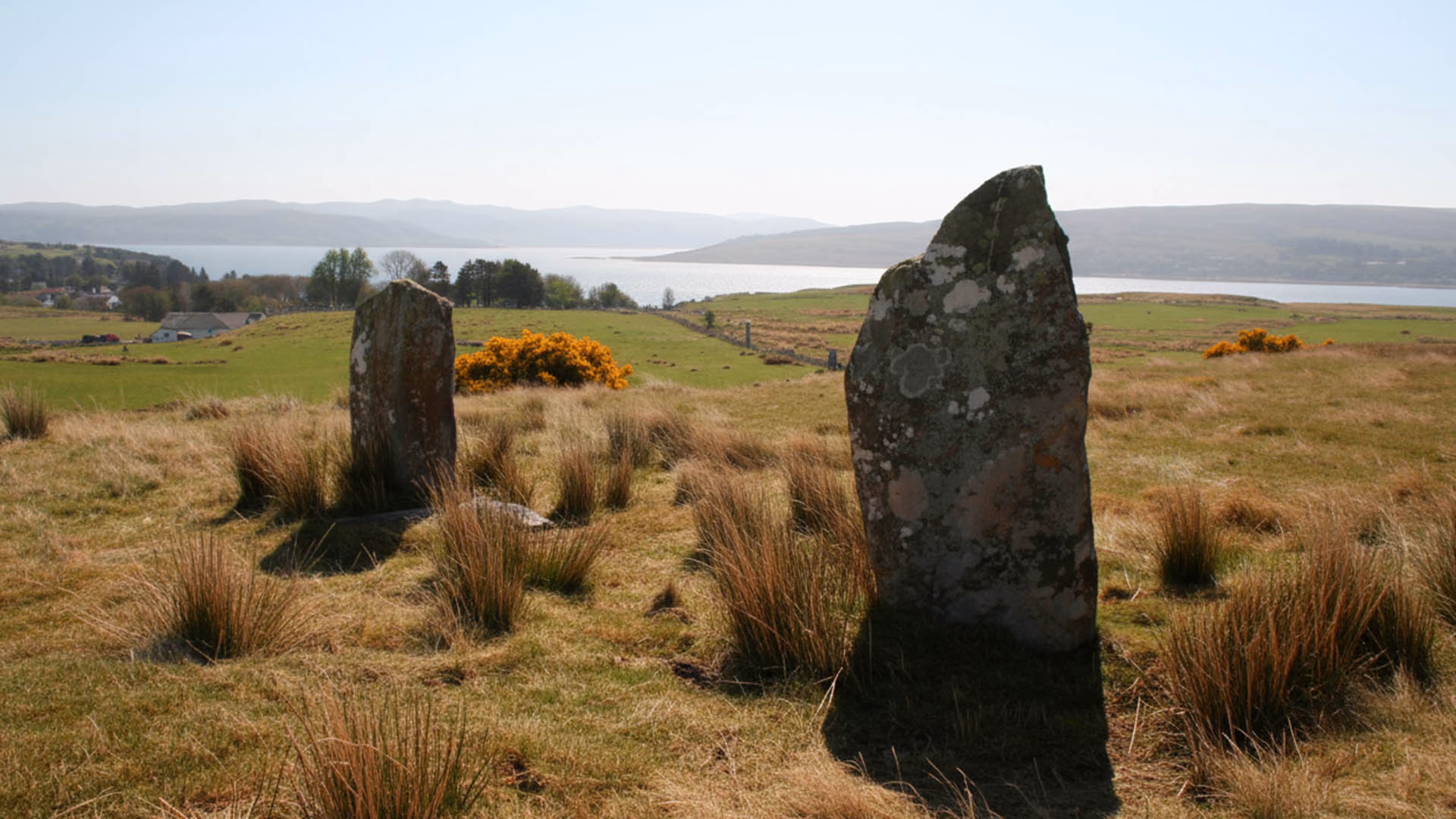 Baliscate Standing Stones, shown with upright stones in the foreground and open fields stretching into the background under natural light