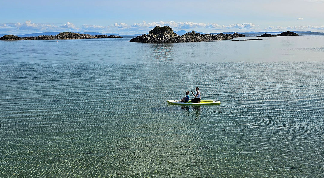 Person paddle boarding in clear water at Uisken Beach near Bunessan, Isle of Mull